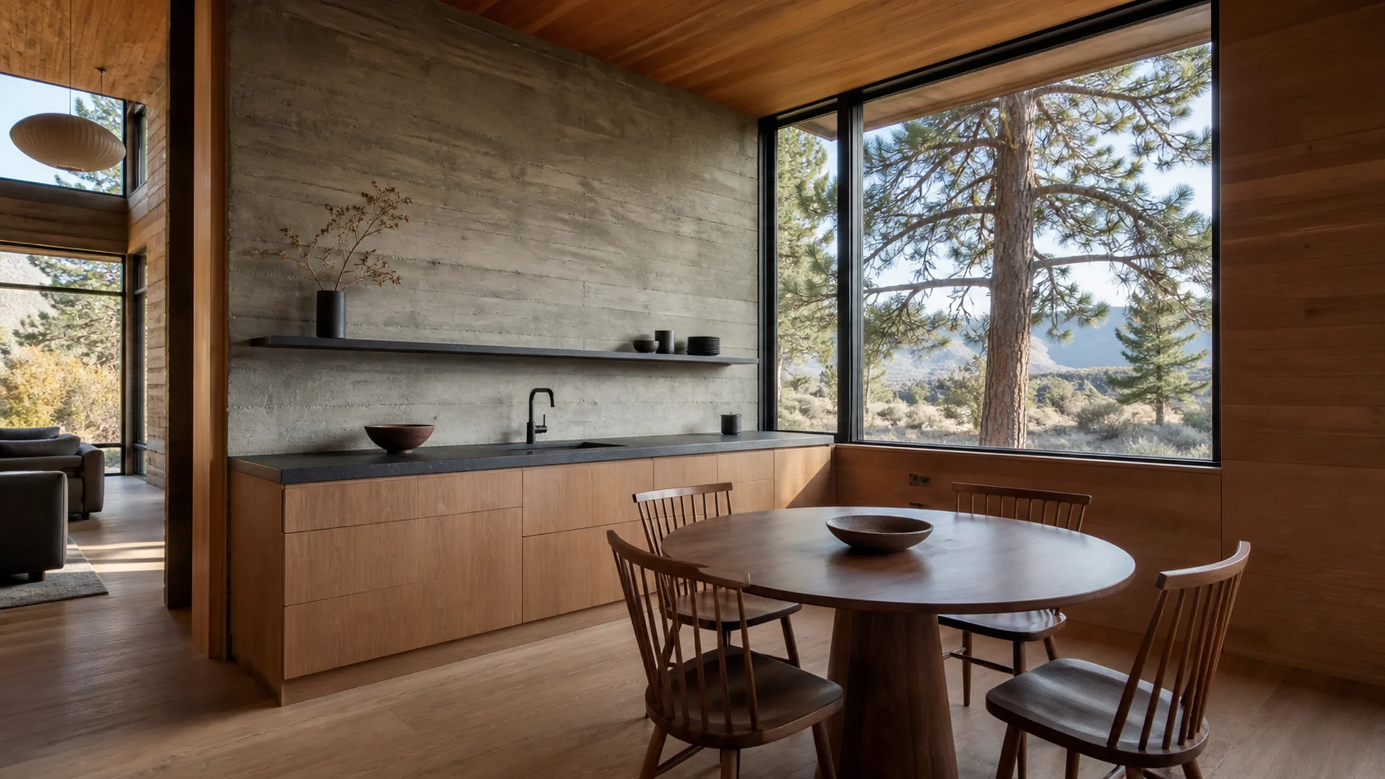 Kitchen with concrete wall, timber cabinetry and a round dining table